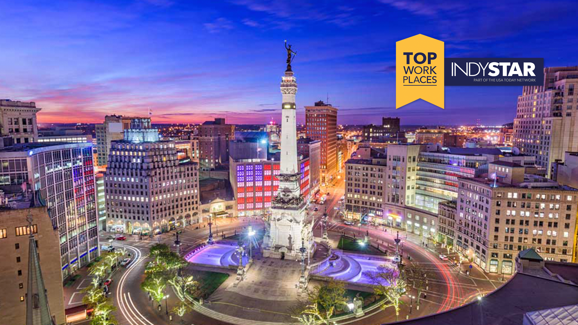 Night city skyline with Monument Circle statue in center and two overlay logos: Top Work Places and INDYSTAR coolly on the right.